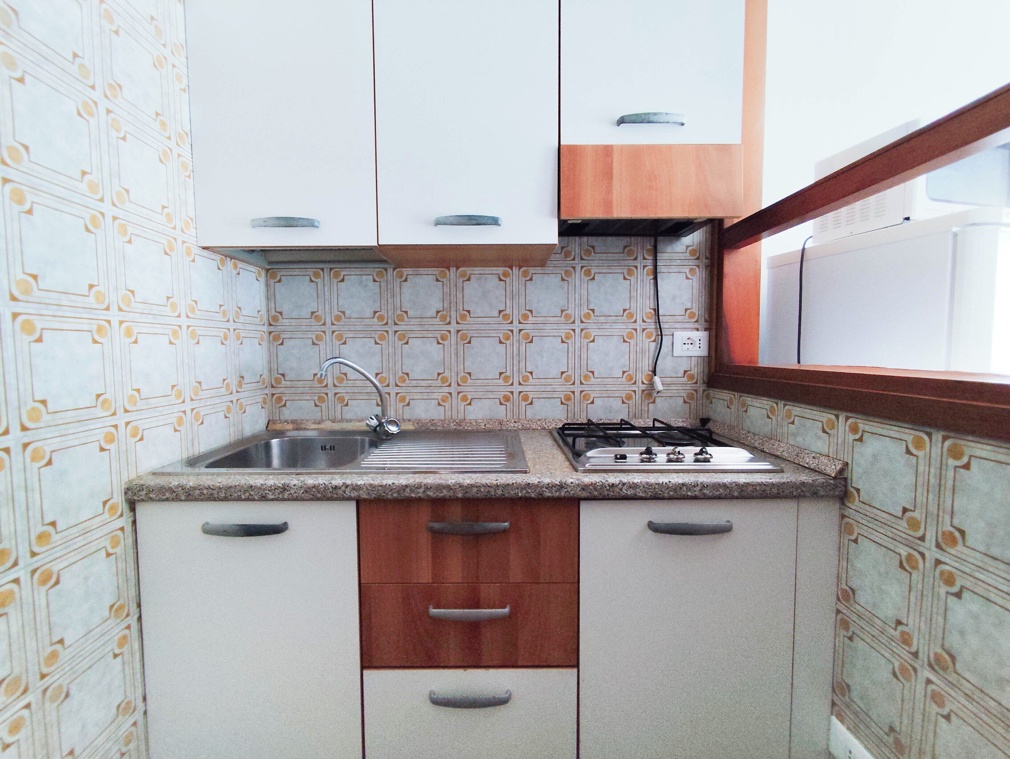 A compact kitchen with a sink, stove, and wooden cabinets.