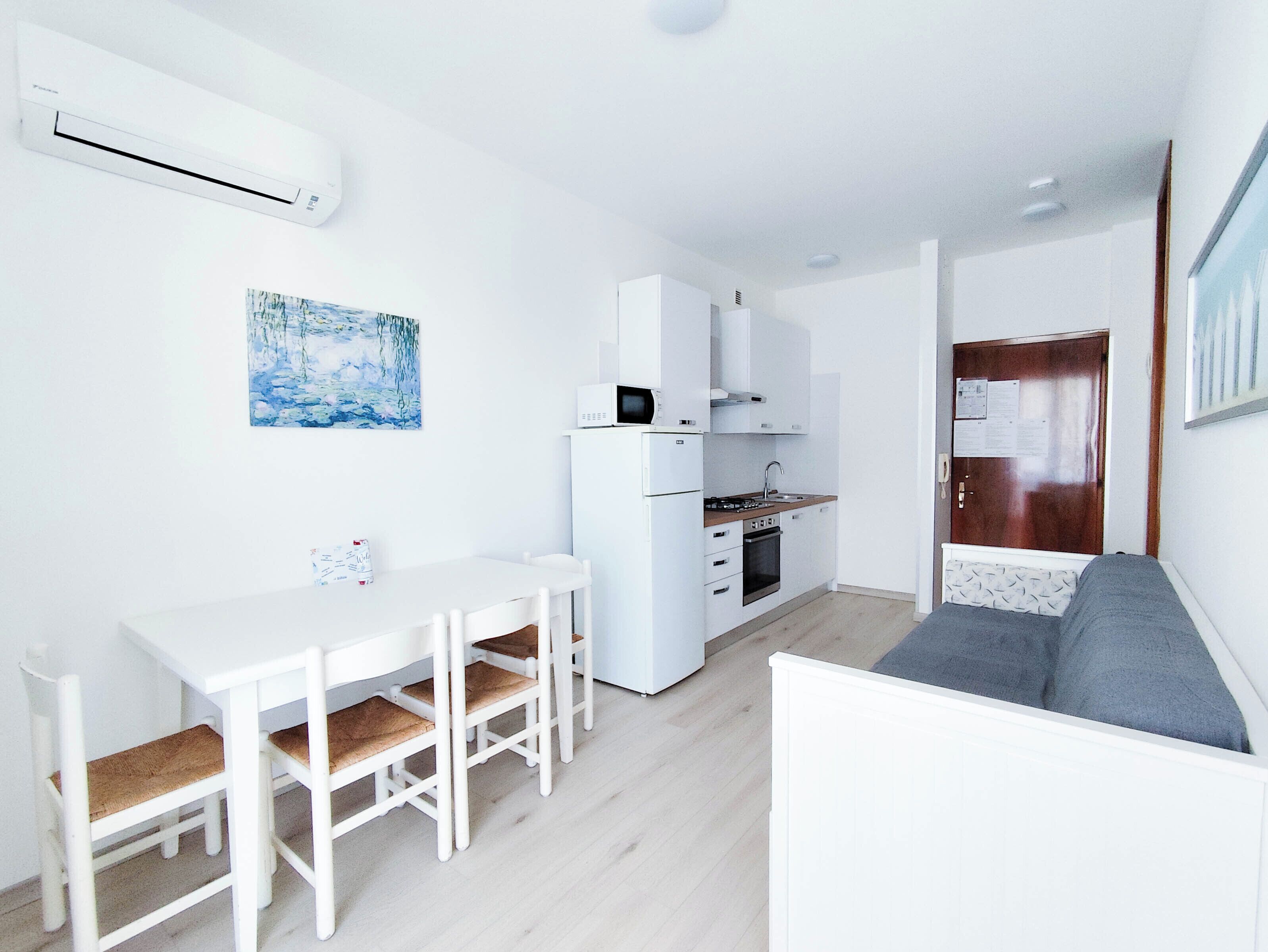 Een ruimtelijk ingerichte leefruimte met kitchenette, eethoek en zithoek.
