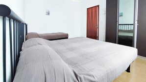 A bedroom with a bed, a wardrobe, and a mirror. - Seaside Apartment With Balcony (Jesolo)