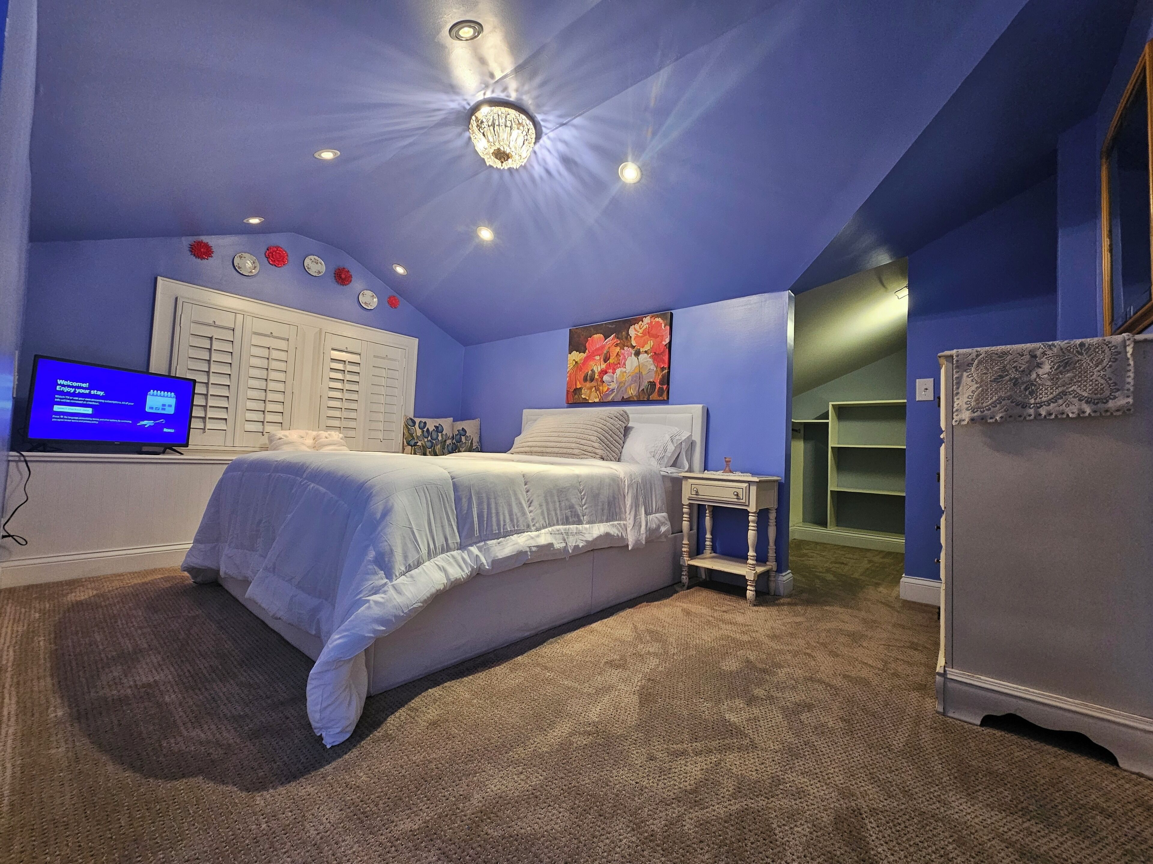Ein Schlafzimmer mit Bett, Nachttisch, Fernseher und Kleiderschrank.