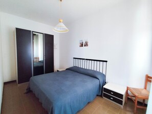 Ein Schlafzimmer mit Bett, Kleiderschrank, Stuhl und Nachttisch.