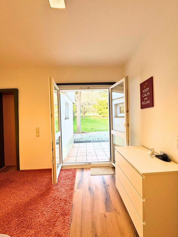 An open door leading to a patio with a 'KEEP CALM AND RELAX' sign, a wooden floor, and a white counter. - House with garden & private parking space in Cologne (Köln)