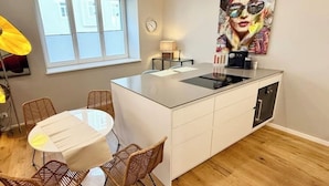 Une cuisine moderne dotée d’un îlot central, de meubles blancs et d’un coin repas avec des chaises en osier.