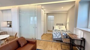 Une chambre moderne et compacte, comprenant un lit, un petit bureau, une chaise et un canapé.