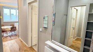 Un couloir comprenant un coin repas, un miroir et une porte donnant sur une autre pièce.
