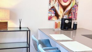 Une cuisine moderne dotée d’un îlot central avec un plan de travail en verre, de tabourets de bar et d’une machine à café.