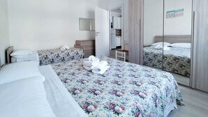 Een hotelkamer met twee bedden, een klein bureau, een spiegel en een kledingkast.