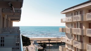 A beachfront hotel with balconies overlooking the sea, a parking area, and a clear view of the beach. - Spacious Apartment With Balcony by the sea (Jesolo)