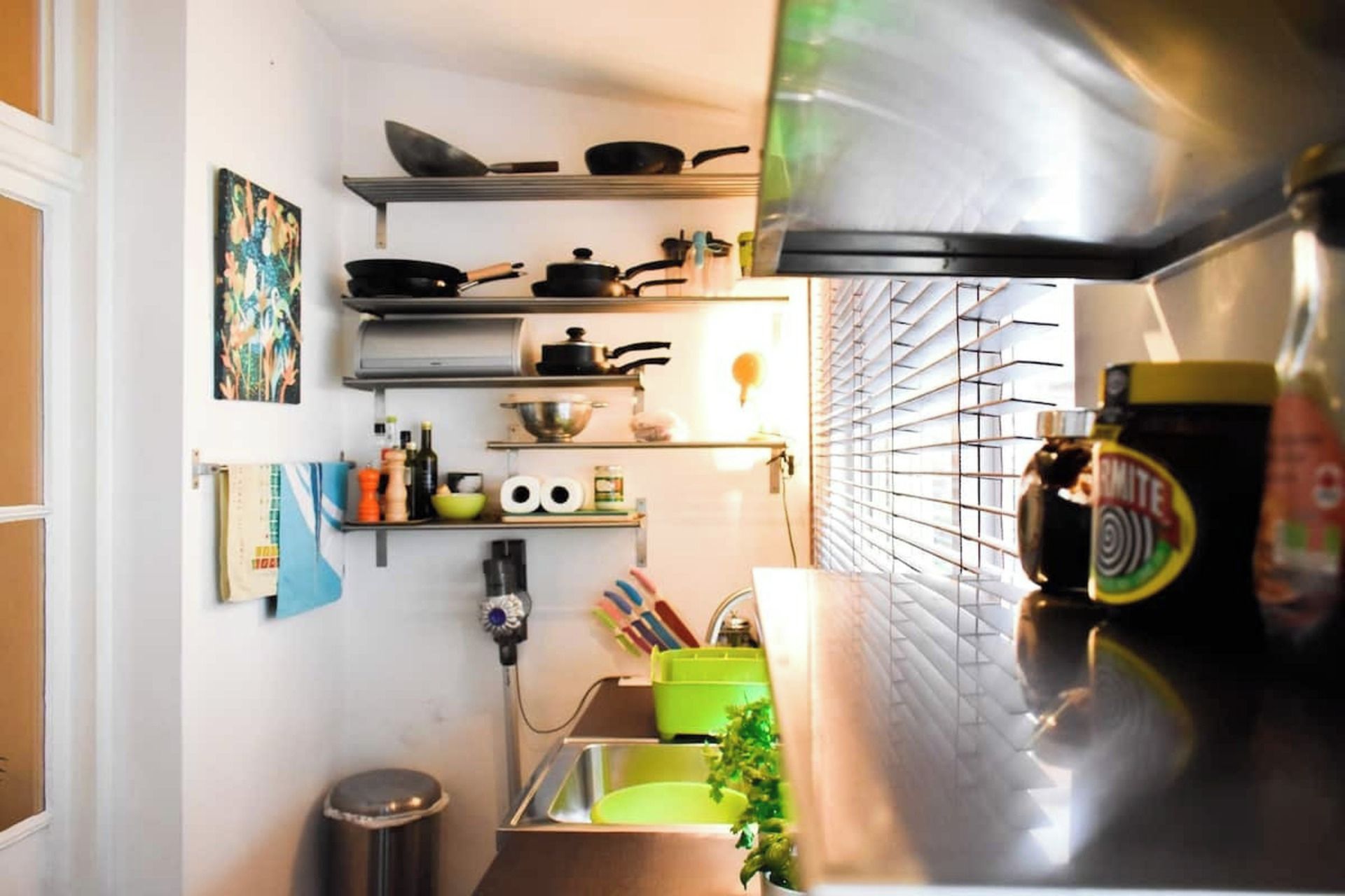 A compact kitchen with a stove, shelves, and a sink.