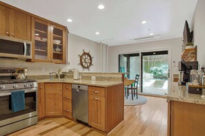 A modern kitchen with wooden cabinets, stainless steel appliances, and a large island. - Luxe Row Home Steps to USNA Gate 3! (Annapolis)