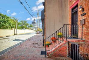 A brick building with a red door, a black metal staircase, and potted flowers. - Luxe Row Home Steps to USNA Gate 3! (Annapolis)