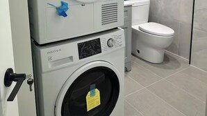 A laundry area with two stacked washing machines and a toilet.