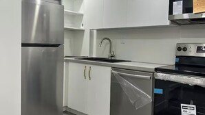 A modern kitchen with stainless steel appliances, white cabinets, and a blue oven.