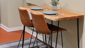 A dining area with a wooden table, two brown chairs, a small potted plant, and a striped rug. - Quaint 1-bedroom house in Ballard neighborhood of Seattle for a perfect getaway (Seattle)