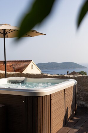 A hot tub on a wooden deck with a view of a mountain and a body of water. - Spacious and beautifully restored stone house nestled in a quiet village Orasac (Orašac)