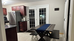 A compact kitchen with dark wooden cabinets, a stainless steel refrigerator, and a built-in dishwasher. - Terrific 3-bedroom family-friendly house close to everything in charming McHenry (McHenry)