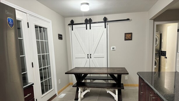 A kitchen with a dark wooden table, white cabinets, and a sliding barn door. - Terrific 3-bedroom family-friendly house close to everything in charming McHenry (McHenry)