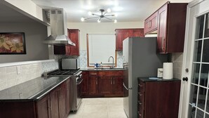 A kitchen with dark wooden cabinets, a stainless steel stove, and a refrigerator. - Terrific 3-bedroom family-friendly house close to everything in charming McHenry (McHenry)