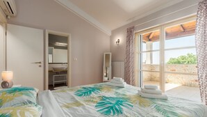 Ein Hotelzimmer mit einem großen Bett, einem Badezimmer mit Waschbecken und Spiegel sowie einem Balkon mit Blick.