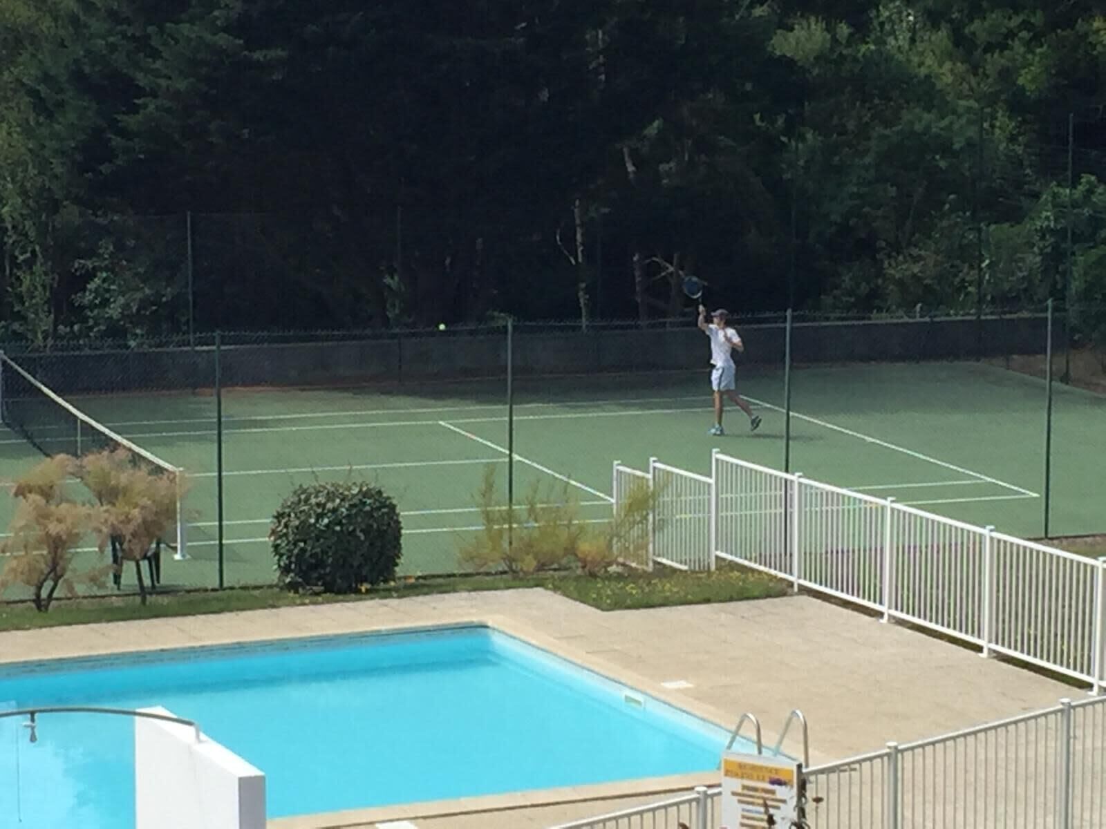 A tennis court with a pool in the foreground.