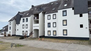 Un edificio residencial de varios pisos con techo plano, múltiples ventanas y una escalera que lleva a un piso superior.