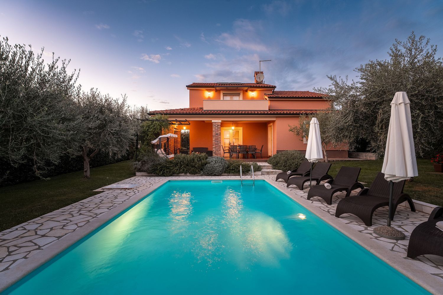 A house with a swimming pool, outdoor seating, and a garden.