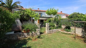 Una propiedad residencial con un muro de piedra, un patio cubierto de césped y una variedad de plantas.