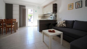 Una sala de estar moderna con un sofá, una mesa de centro y una zona de comedor con sillas.