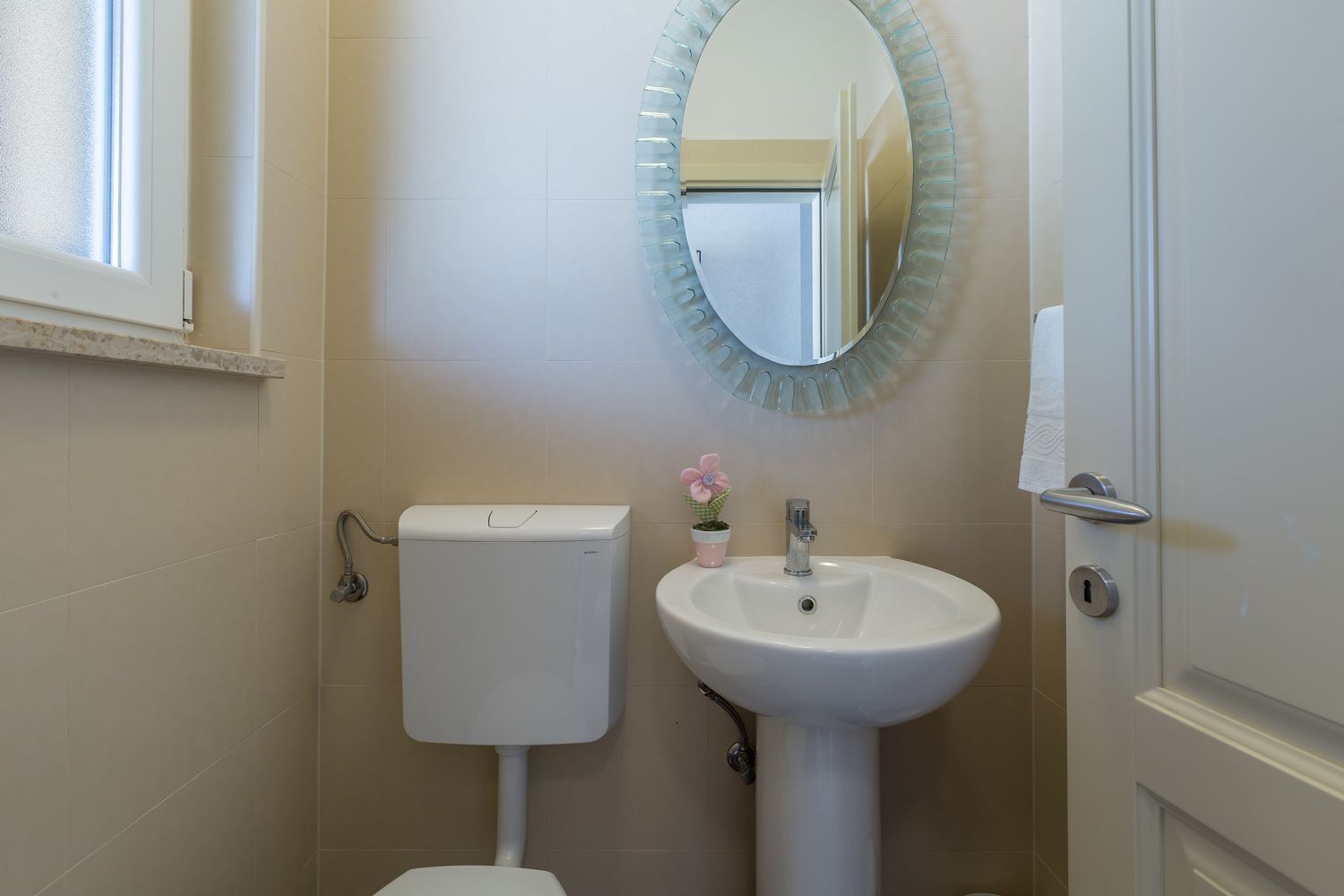 A bathroom with a toilet, sink, and a mirror with a decorative frame.