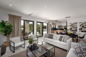 A modern living room with a sofa, coffee table, and chairs, a dining area with a table and chairs, and a kitchen visible through glass doors. - Extravagant villa with sauna, private pool, billiards, BBQ (Porec)