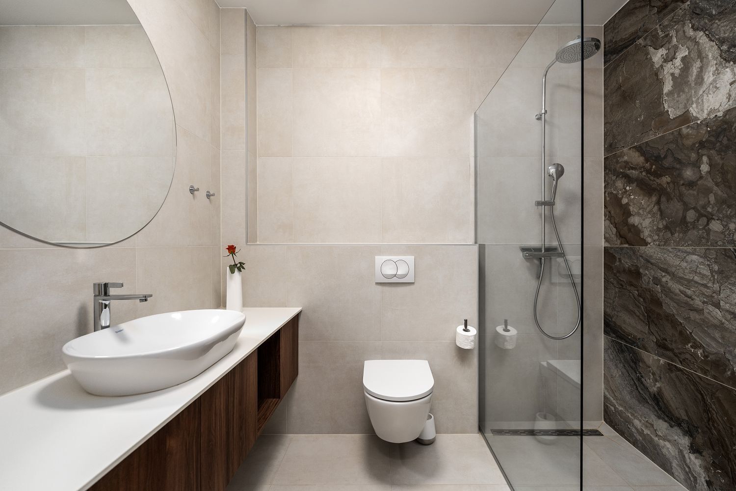 Un baño moderno con un lavamanos grande, inodoro y cabina de ducha de vidrio.