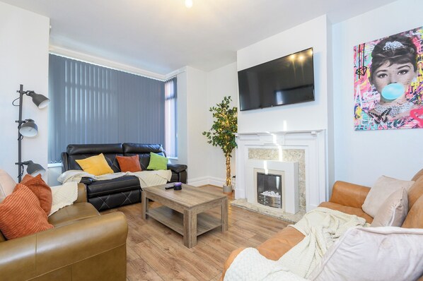 A modern living room with a fireplace, leather sofas, and a flat-screen TV.