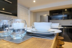 A modern kitchen with a wooden countertop, white plates, and clear glasses.