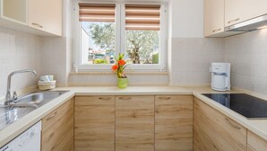 Una cucina moderna con mobili in legno, lavastoviglie integrata, macchina da caffè e finestra con persiane.