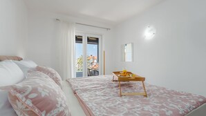 Una camera da letto con un letto, un comodino con un vassoio, una finestra e vista sull'esterno.