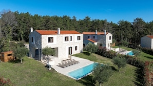 A two-story stone house with a swimming pool, surrounded by a well-maintained lawn and trees. - Special stone house with private pool, panoramic view, garden, barbecue, washing machine (Višnjan)