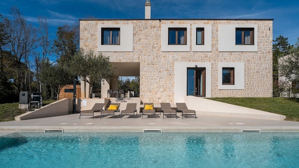 A modern two-story building with a stone facade, a swimming pool, and outdoor seating. - Special stone house with private pool, panoramic view, garden, barbecue, washing machine (Višnjan)