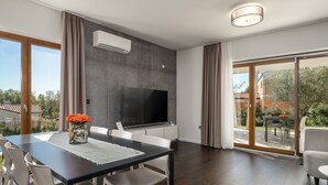 A modern living room with a dining area, a flat-screen TV, and a large sliding glass door leading to an outdoor patio. - Special stone house with private pool, panoramic view, garden, barbecue, washing machine (Višnjan)