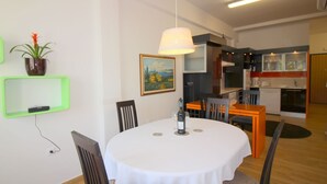Ein Essbereich mit einem runden Tisch, Stühlen, einer Pendelleuchte, einem Blumentopf und einem Bild an der Wand.
