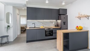 Una cocina moderna con armarios oscuros, un salpicadero de mármol y un horno empotrado.