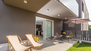 Un balcón con dos sillones, una mesa y sillas, y una planta en maceta.
