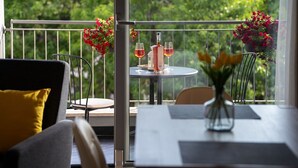 A balcony with a table set for two, featuring a vase with flowers, two wine glasses, and a bottle. - Luxury apartment with sea view, only 50 metres from the marina and 300 metres from the beach (Vrsar)