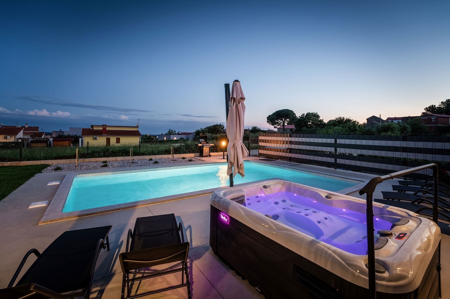 Une piscine avec un jacuzzi et des chaises longues.