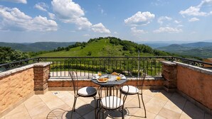 Une terrasse avec une table dressée pour deux personnes, donnant sur une colline verdoyante.