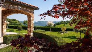 Un arc en pierre mène à un jardin bien entretenu, agrémenté de haies et d’arbres.