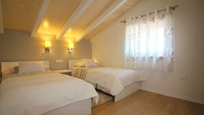 Una camera da letto con due letti, pavimento in legno e soffitto spiovente con travi a vista.