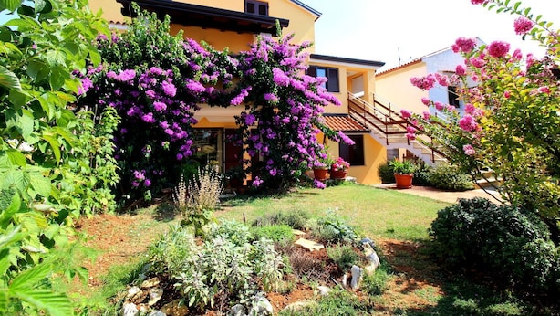 A two-story building with a yellow facade, a wooden staircase, and a garden with purple flowers. - Idyllic apartment just 700 metres from the beach with balcony, garden and WiFi (Porec)