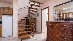 Une cuisine avec un escalier en bois, un réfrigérateur blanc et une commode en bois dotée de tiroirs.