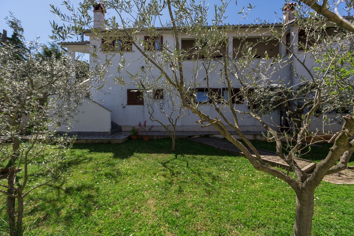 Ein weißes Gebäude mit Garten, inklusive Baum und kleinem Teich.