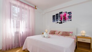 Un dormitorio con una cama grande, una mesita de noche y una obra de arte colgada en la pared.
